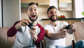 excited-smiling-men-playing-video-games-tv-home-couch-friends-with-joysticks-play-game-with-happy-emotions-faces