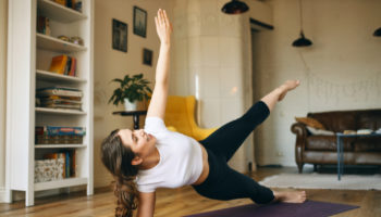 energetic-athletic-young-woman-exercising-indoors-doing-side-plank-pose-which-helps-build-strength-core-arms-legs