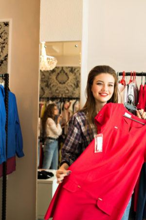 side-view-fashionable-beautiful-woman-shirt-holding-want-buying-elegant-red-dress-brunette-girl-with-long-hair-choosing-look-evening-spanding-time-shoppinh-mall